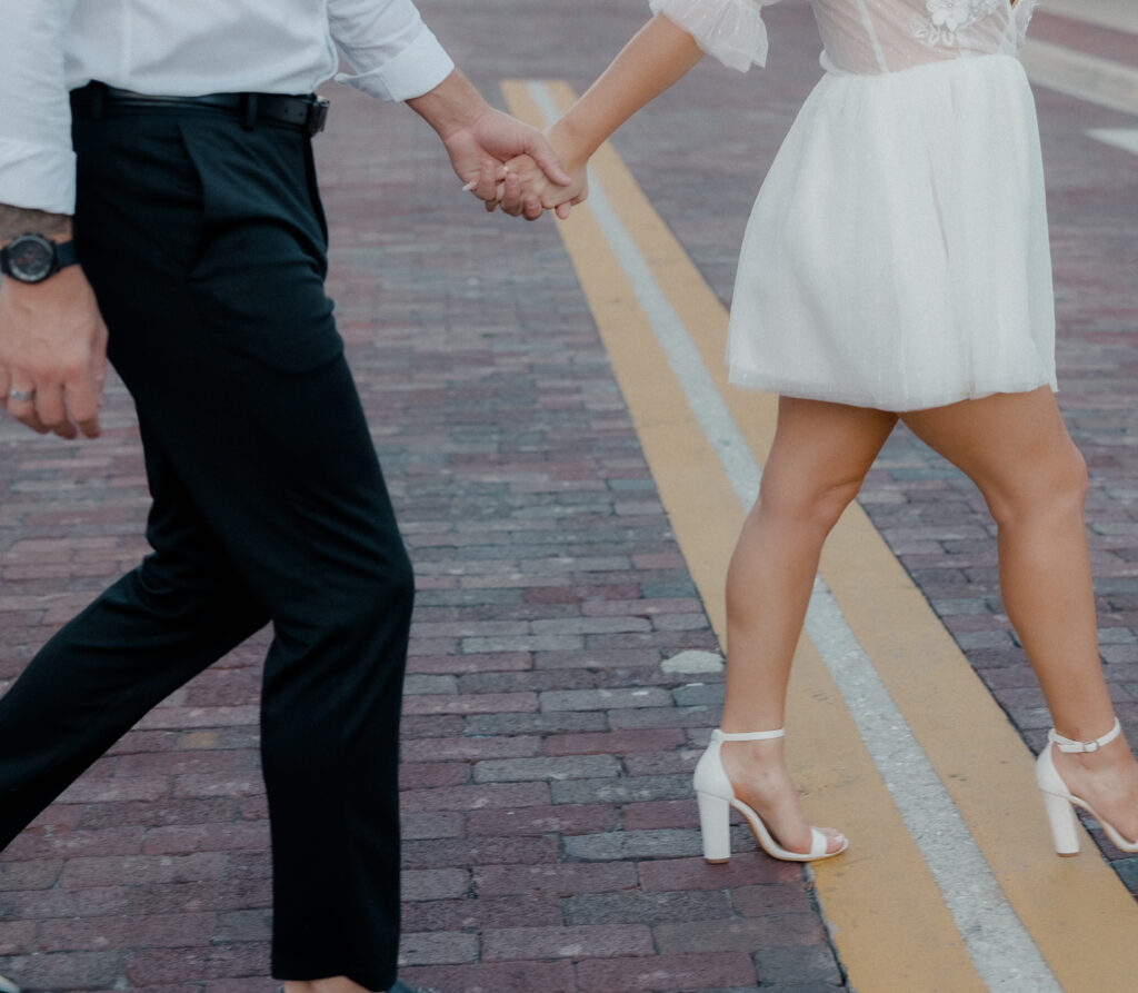 Holding hands during engagement photos walking down the street in downtown Fort Myers.