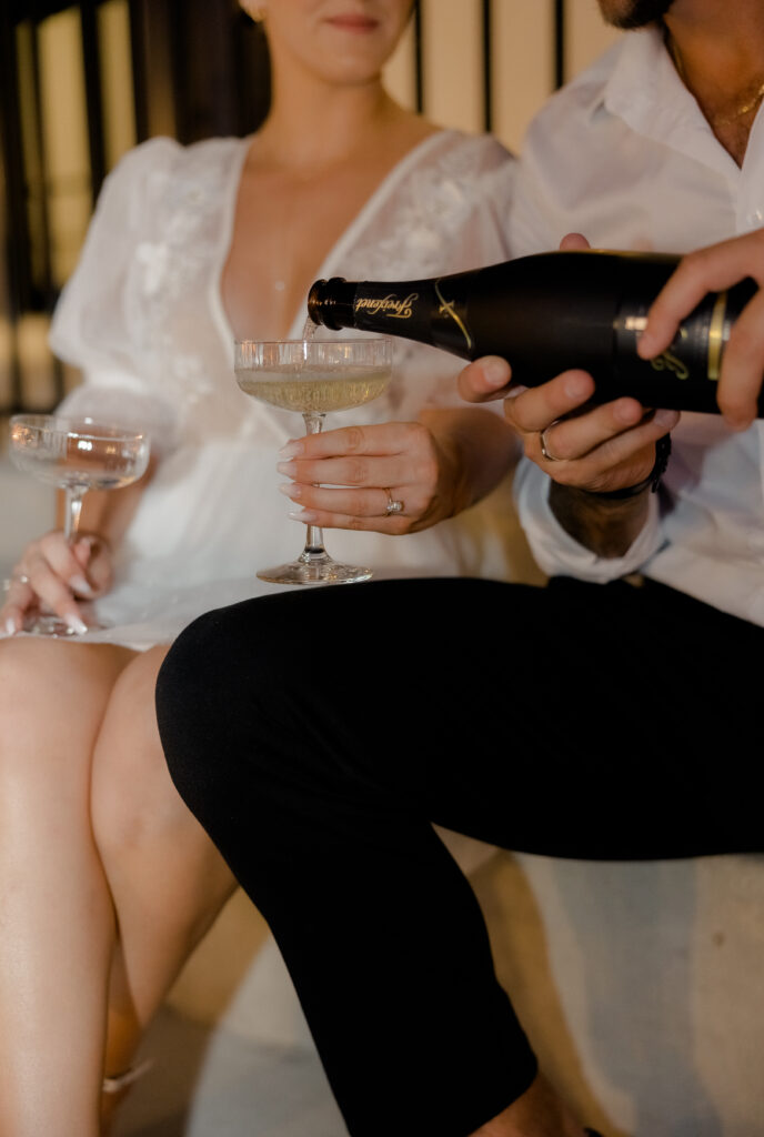 Champagne pour during downtown engagement photos.