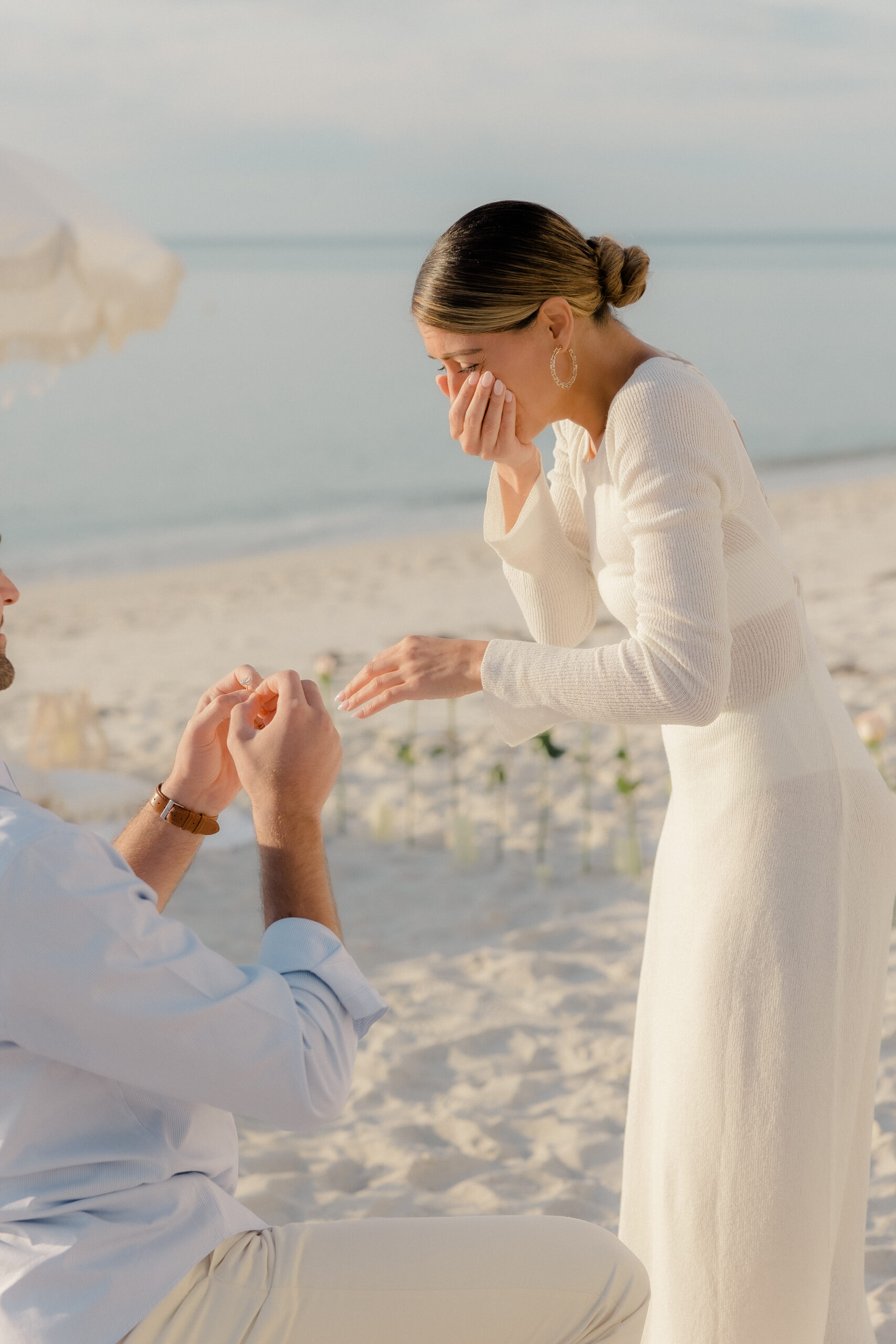 Close-up shot of Nicole's tearful, joyful reaction and Brandon's beaming smile as he proposes, artfully photographed by Naples Florida photographer Maddie Briggs.