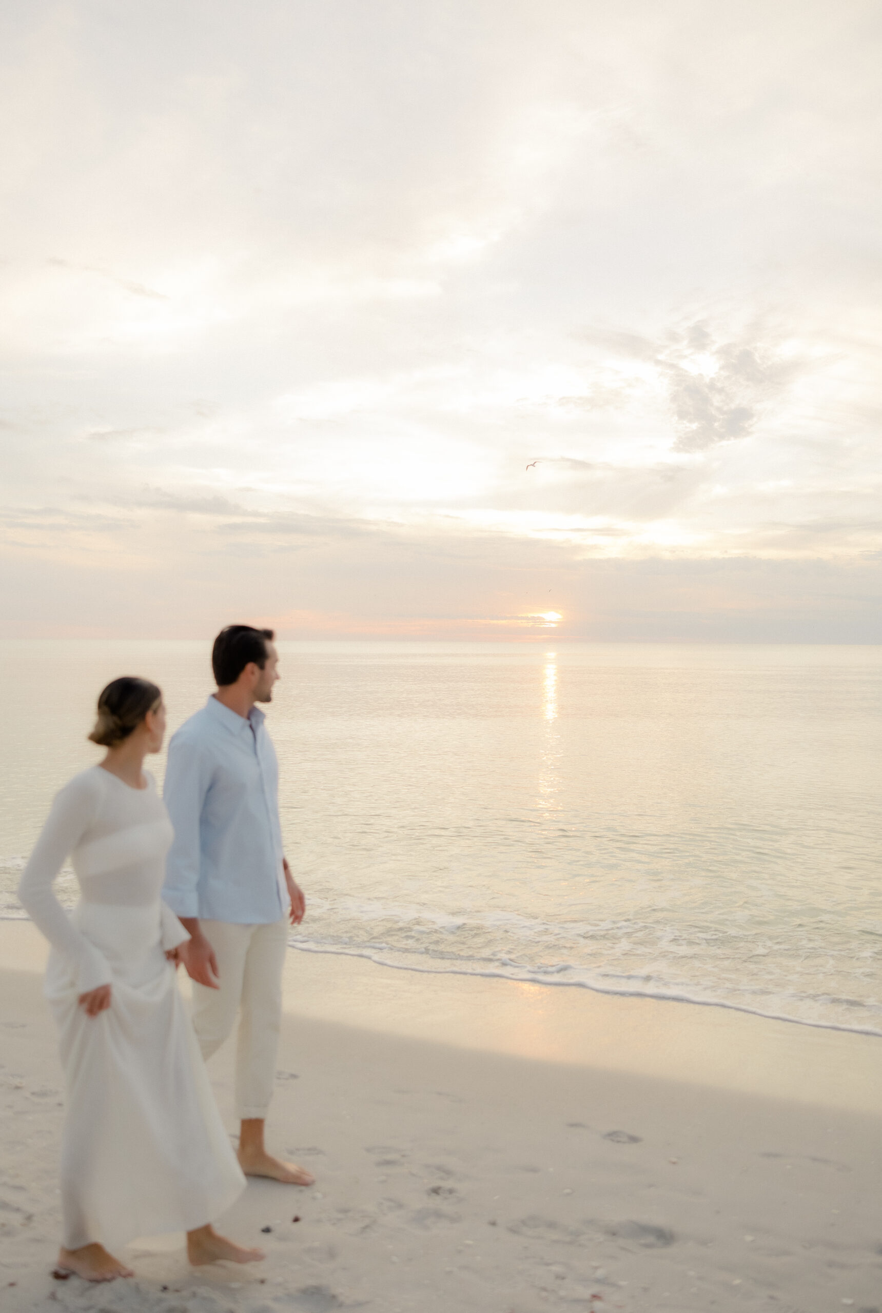 newly engaged couple stroll down the beach as a Naples Florida photographer, Maddie briggs photography, captures the moment.